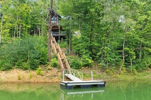 Una escalera de madera que lleva a una cabaña rodeada de un bosque denso.