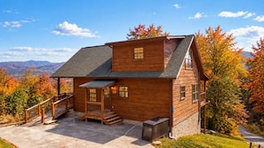 A wooden cabin with a porch, a staircase, and a view of the mountains. - Radiant Sky Views | Hot Tub, Game Room, MORE! (Sevierville)