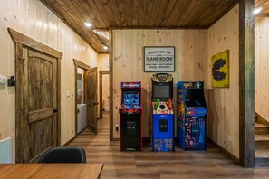 A game room with wooden walls, a welcome sign, and three arcade machines. - Lakefront-Private Dock-Pets-VIEWS-Beach Access (Sevierville)