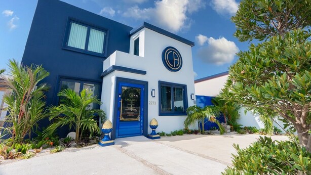 A modern two-story building with a blue and white exterior, a visible address number, and a well-maintained garden with various plants. - Casa Azul - Your Own Private Boutique Hotel for 12 - Breakfast Included (San Juan)