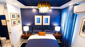 A bedroom with a large bed, two bedside tables with lamps, a chandelier, and artwork on the walls. - Casa Azul - Your Own Private Boutique Hotel for 12 - Breakfast Included (San Juan)