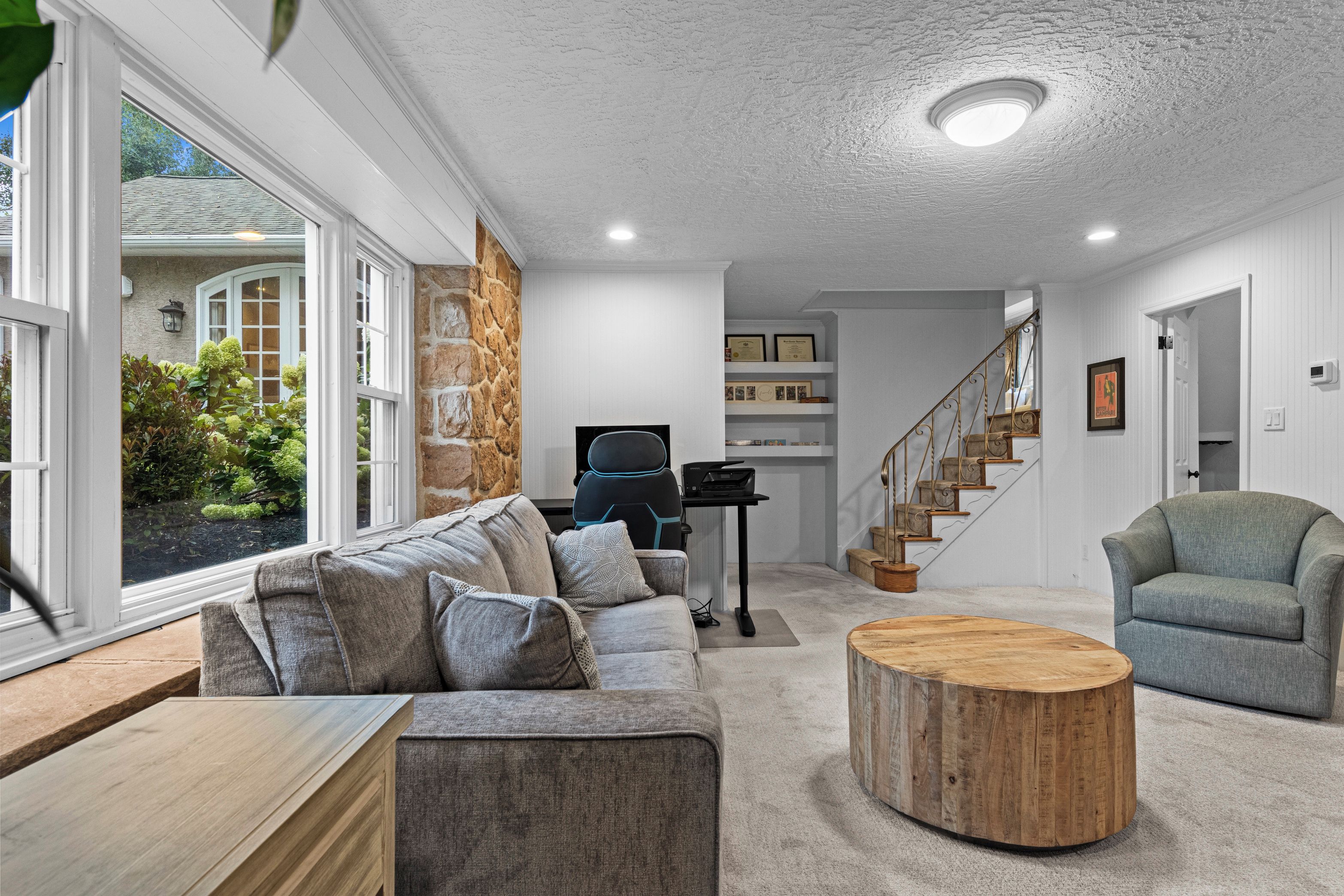 A modern living room with a sofa, a coffee table, and a staircase leading to a second floor.