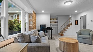 A modern living room with a sofa, a coffee table, and a staircase leading to a second floor.
