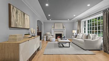 A spacious living room with a fireplace, a sofa set, a coffee table, and a large window with curtains.