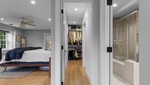 A bedroom with a bed, a closet, and a bathroom with a shower.