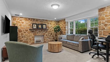 A living room with a stone wall, a fireplace, a sofa, a coffee table, and a TV.