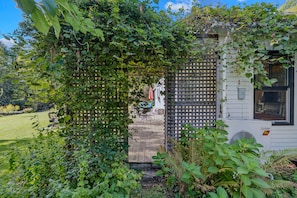 Ein Garten mit Holzzaun, eine Terrasse mit Gartenmöbeln und ein Gebäude mit einer Mitsubishi Electric Klimaanlage.