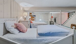 Ein Schlafzimmer mit zwei Betten, einem Schminktisch, einem Spiegel und einer Treppe.