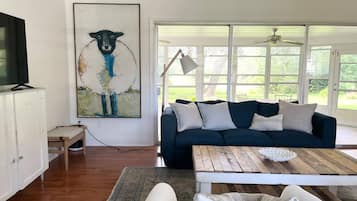 A living room with a dark blue sofa, a white coffee table, and a painting on the wall.