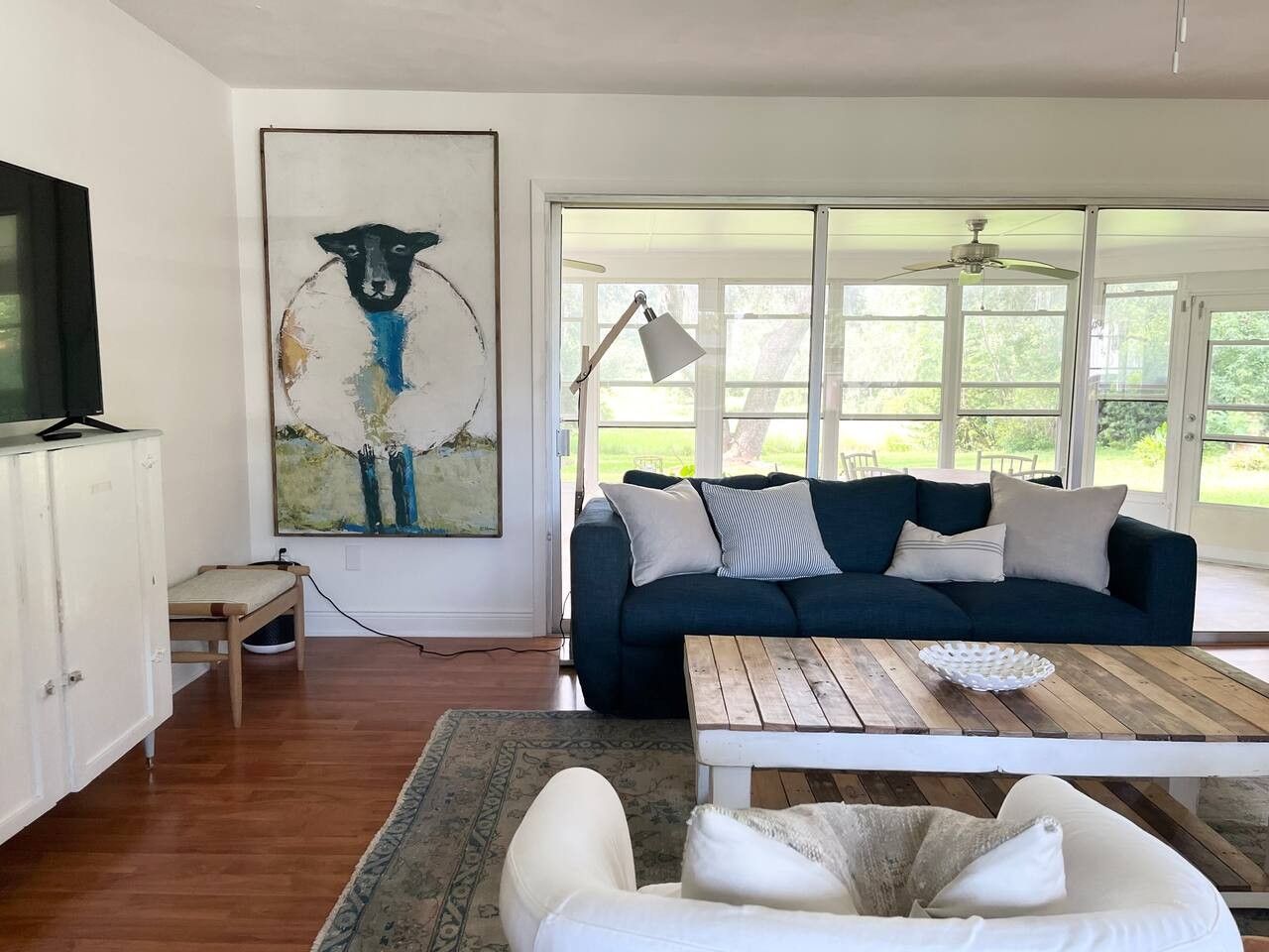 Un salon avec un canapé bleu foncé, une table basse blanche et un tableau accroché au mur.