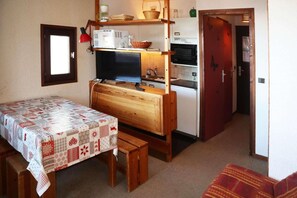 A compact kitchen with a wooden table and bench, a refrigerator, and a microwave. - 40m from ski slopes, 5th floor, balcony, 20m², Les Orres (Les Orres)