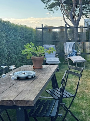 A wooden picnic table with a potted plant, a folding chair, and a bench. - Renovated house with garden in Österlen (Skåne län)