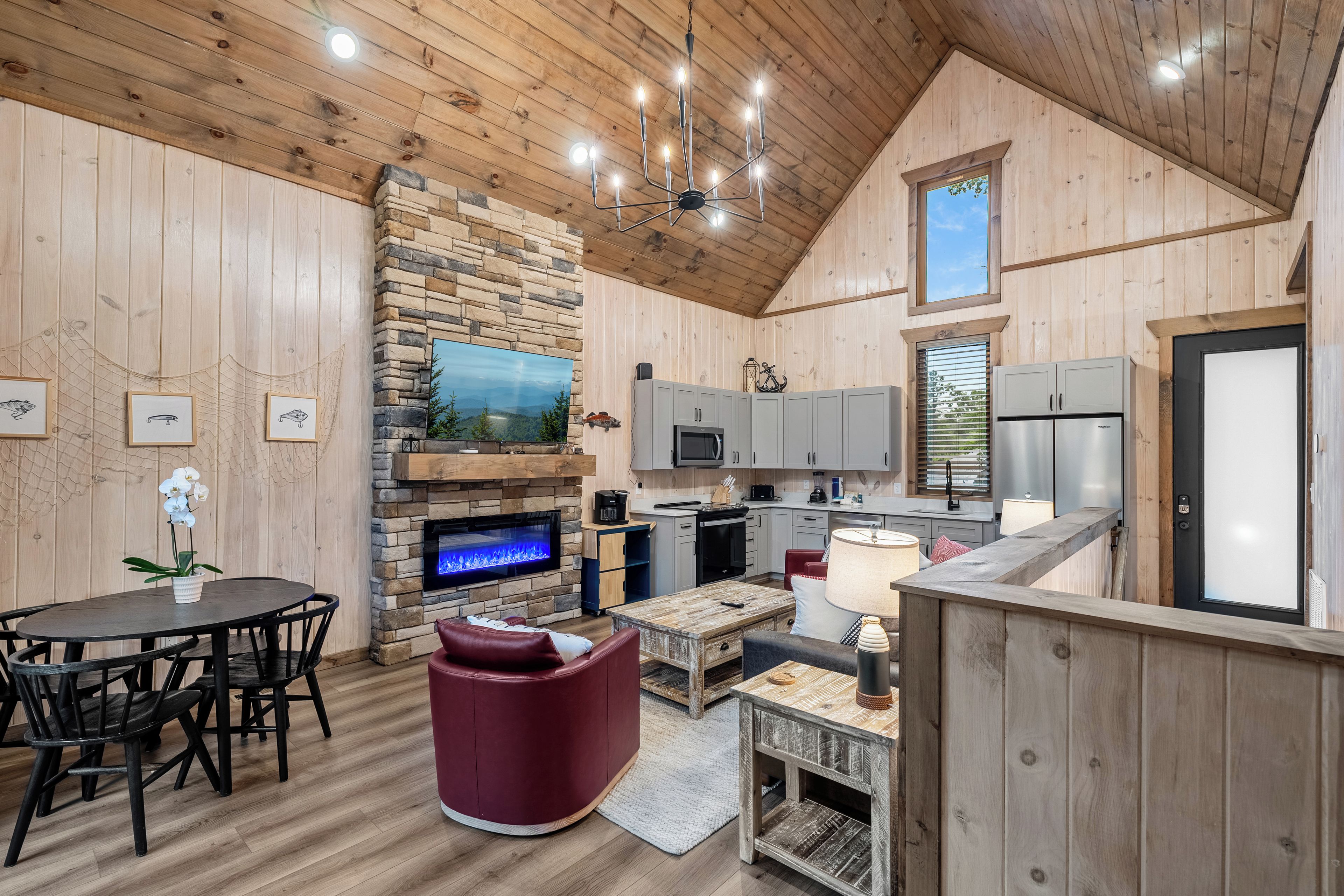 Un intérieur de chalet chaleureux avec une cheminée en pierre, un coin repas, une cuisine et un espace salon.