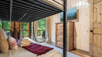 A bedroom with a bed, a window, a wooden wardrobe, and a view of the outdoors.