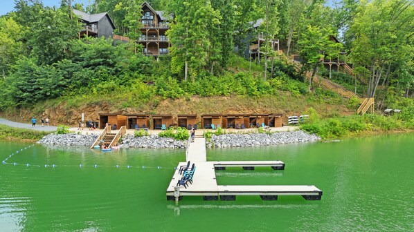 Un albergue junto al lago con un muelle, asientos al aire libre y un edificio de madera de varios niveles.