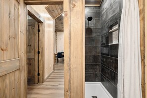 A wooden interior hallway leading to a bathroom with a shower and tiled walls. - Lakefront-Private Dock-Pets-Hot Tub-Beach Access (Sevierville)