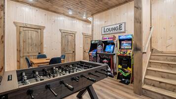 A room with a foosball table, two doors, a lounge area, and arcade games.