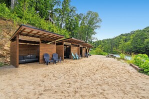 A beachside wooden structure with seating and a picnic table, surrounded by greenery and a clear sky. - Lakefront-Private Dock-Pets-Hot Tub-Beach Access (Sevierville)
