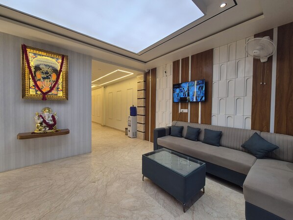 A modern interior with a sofa, a coffee table, a TV mounted on the wall, and a statue on a shelf.