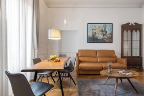Ein modernes Wohnzimmer mit Esstisch, Ledersofa und einem Bild an der Wand.