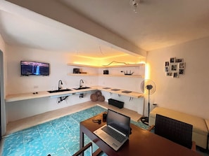 A room with a pool, a laptop on a table, a TV on the wall, and shelves with various items. - Casa Cedro 12 | Mérida (Mérida)