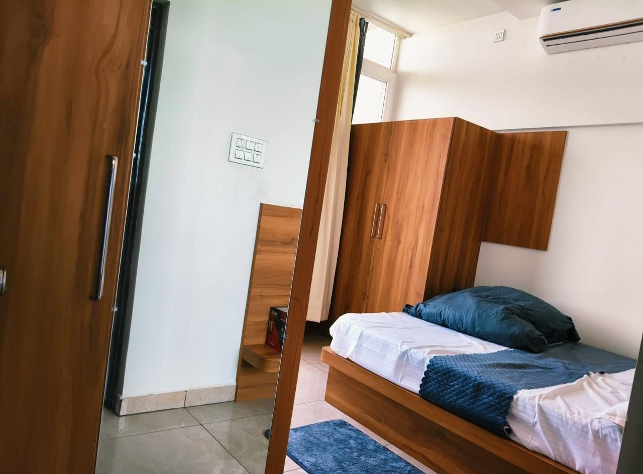 A room with a bed, wooden wardrobe, and a door.