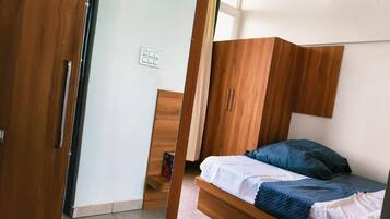 A room with a bed, wooden wardrobe, and a door.