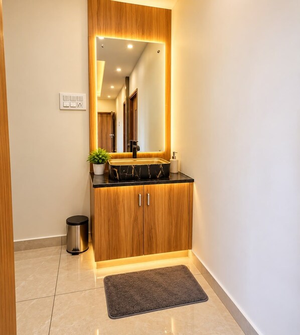 Un baño moderno con un tocador de madera, un espejo grande y una encimera negra.