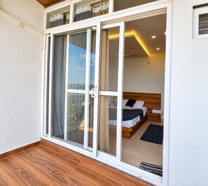 Un dormitorio con cama de madera, un panel corredizo que da a un balcón y vistas a la ciudad.