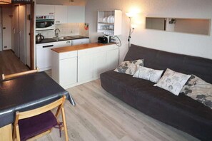 A compact living space with a kitchenette, a sofa with patterned cushions, and a dining area with a table and chair. - 40m from ski slopes, 9th floor, view valley, balcony, 25m², Les Orres (Les Orres)