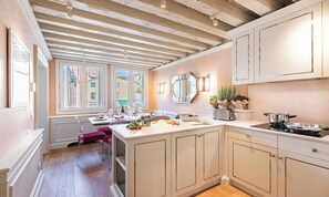 A kitchen with a central island, wooden ceiling beams, and a view through the windows. - SPECTACULAR VENETIAN APARTMENT OVERLOOKING CAMPO SAN MAURIZIO (Venezia)