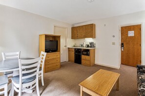 A compact living space with a dining area, kitchenette, and a television.
