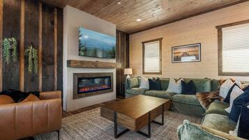 A cozy living room with a fireplace, a green sofa, a brown leather couch, and a wooden coffee table.