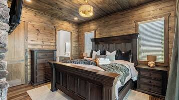 A bedroom with a wooden headboard, a large bed, a dresser, and a stone wall.