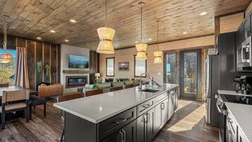 A modern kitchen with a large island, stainless steel appliances, and pendant lighting.