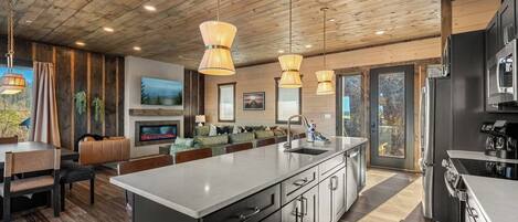 Una cocina moderna con una isla grande, electrodomésticos de acero inoxidable e iluminación colgante.