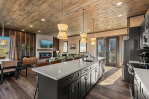 Una cocina moderna con una isla grande, electrodomésticos de acero inoxidable e iluminación colgante.