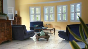 A living room with a sofa, armchairs, a coffee table, and a cabinet. - Villa Ladouchka 3 étoiles, loft créole jusqu'à 7 pers. Entre randos et plages. (Goyave)