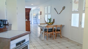 A kitchen with a dining area, a staircase, and a view of the living room. - Villa Ladouchka 3 étoiles, loft créole jusqu'à 7 pers. Entre randos et plages. (Goyave)