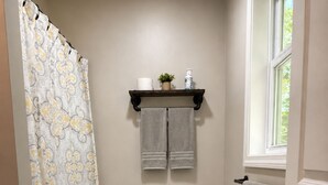 Ein Badezimmer mit Toilette, Duschvorhang, Handtuchhalter und einem Fenster.