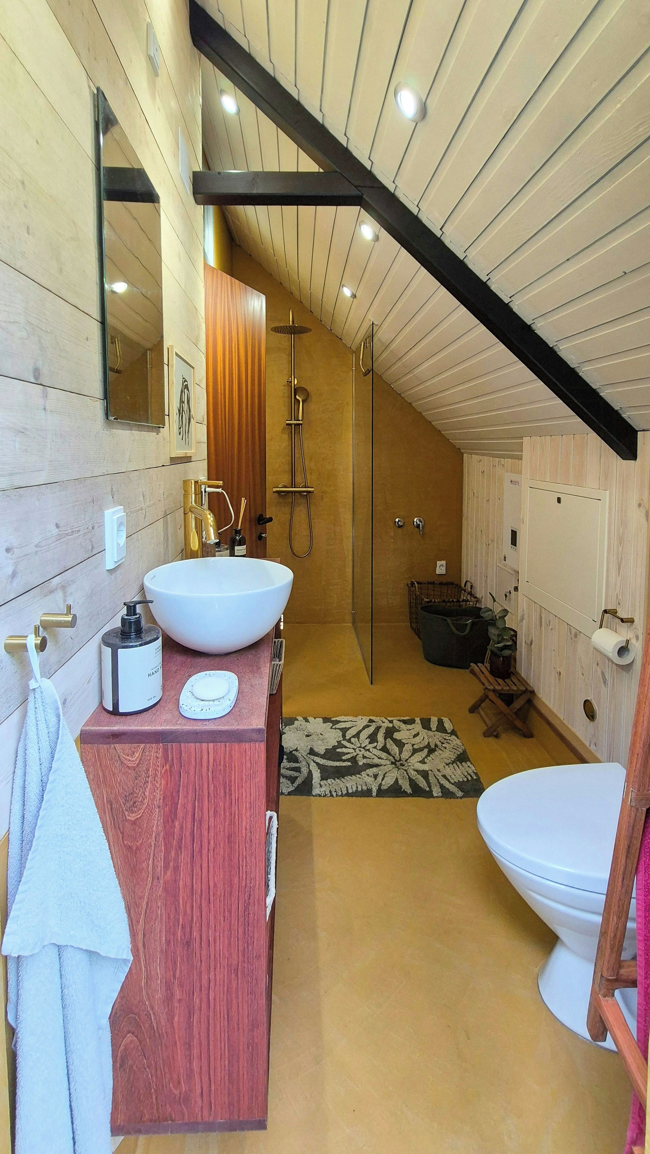 A modern bathroom with a large white sink, a wooden vanity, a glass shower enclosure, and a white toilet.