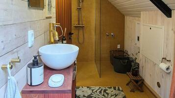A modern bathroom with a large white sink, a wooden vanity, a glass shower enclosure, and a white toilet.