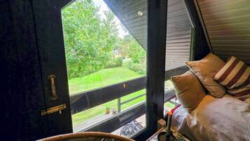 A room with a window overlooking a grassy yard and a wooden deck.