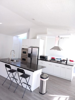 Eine moderne Küche mit Kochinsel, Edelstahlgeräten und einem Fenster für natürliches Licht.