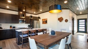 Une cuisine moderne avec des meubles de couleur sombre, des appareils en acier inoxydable et un îlot central doté de sièges.