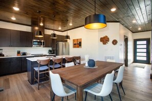 Cozinha moderna com armários escuros, eletrodomésticos de aço inoxidável e uma ilha central com assentos.