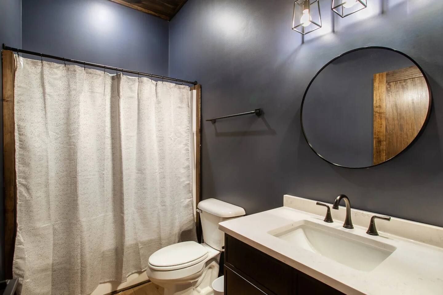 Une salle de bain équipée de toilettes, d’un lavabo, d’un miroir et d’un rideau de douche.