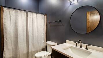 Une salle de bain équipée de toilettes, d’un lavabo, d’un miroir et d’un rideau de douche.