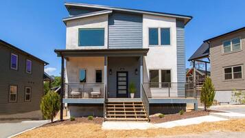 A two-story residential building with a front porch, a staircase, and a small garden area.