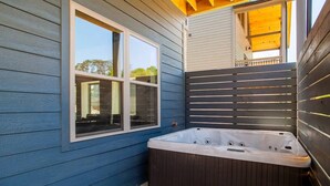 Un bain à remous situé à côté d’une fenêtre donnant sur du mobilier d’extérieur.